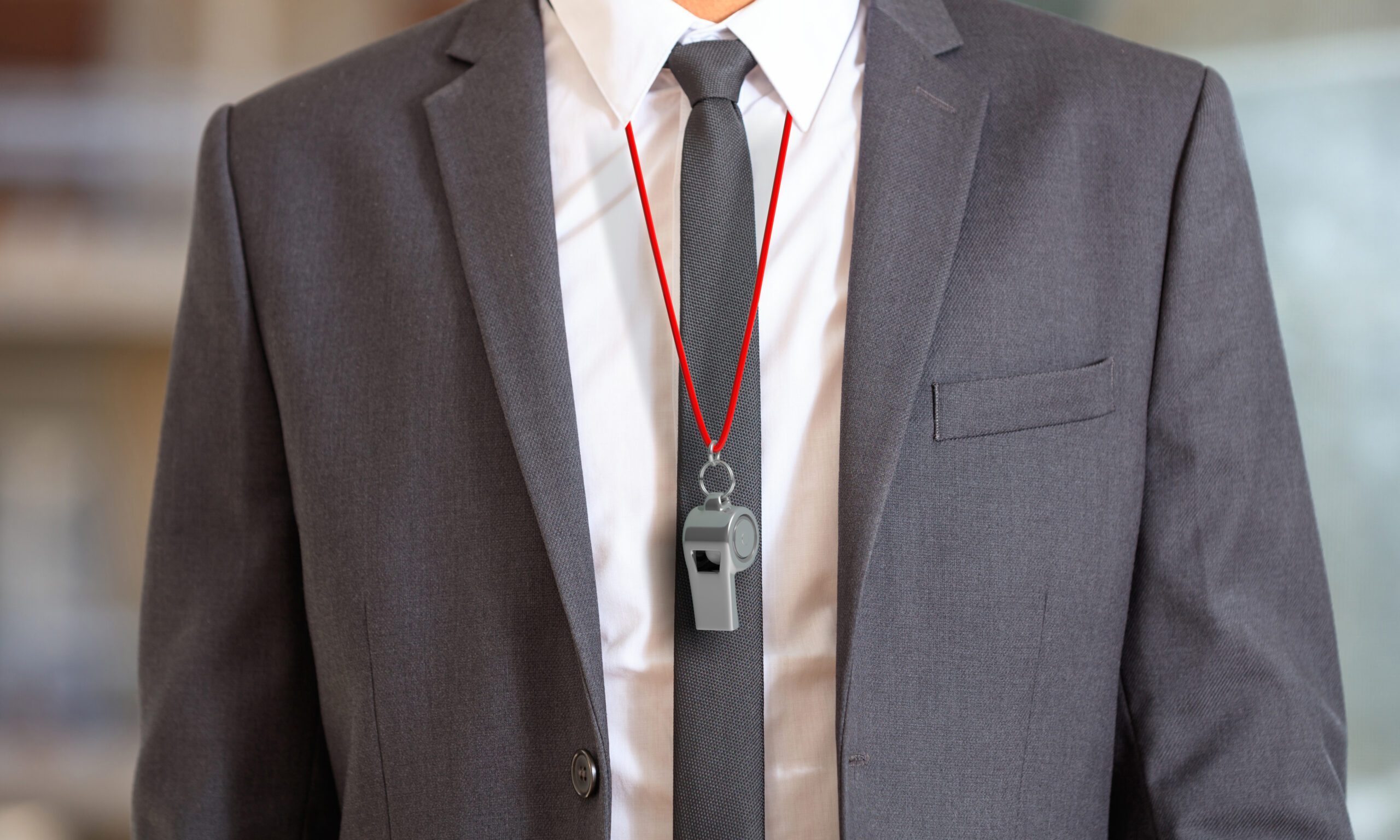 Man in a suit with a whistle around his neck.